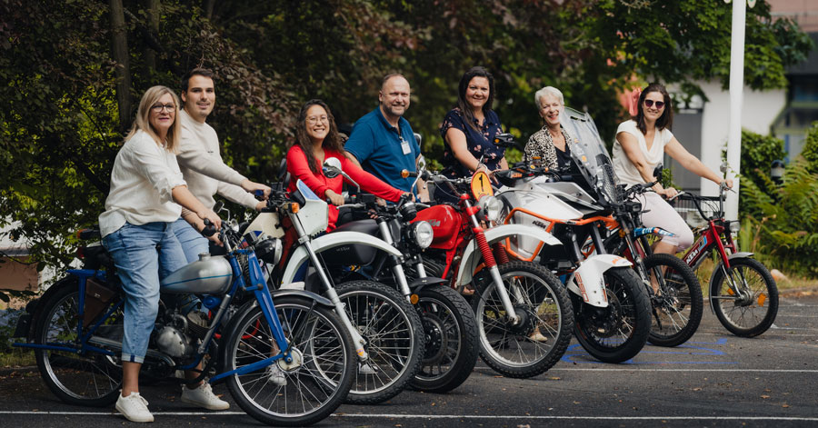 F¨hrungsteam einer Pflegeeinrichtung posiert auf Motorrädern für ein Gruppenfoto
